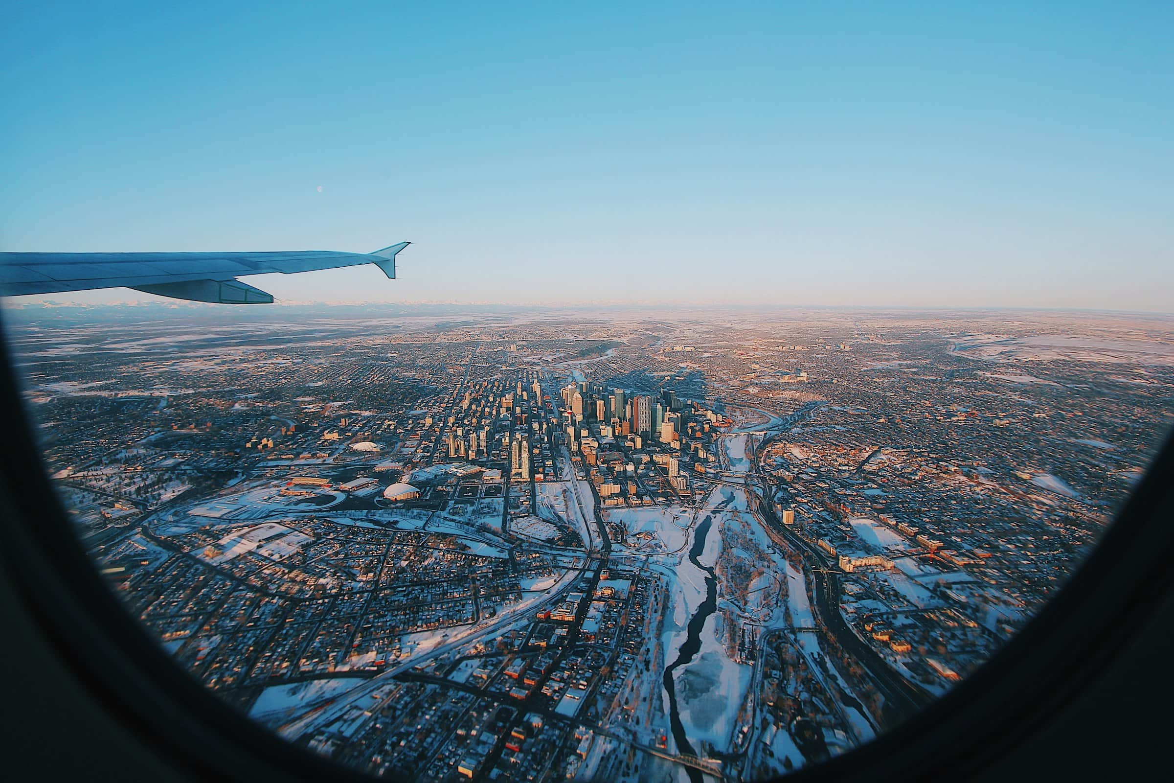 An aerial view from an airplane window of snow-dusted downtown Calgary with the Rocky Mountains on the horizon, Alberta